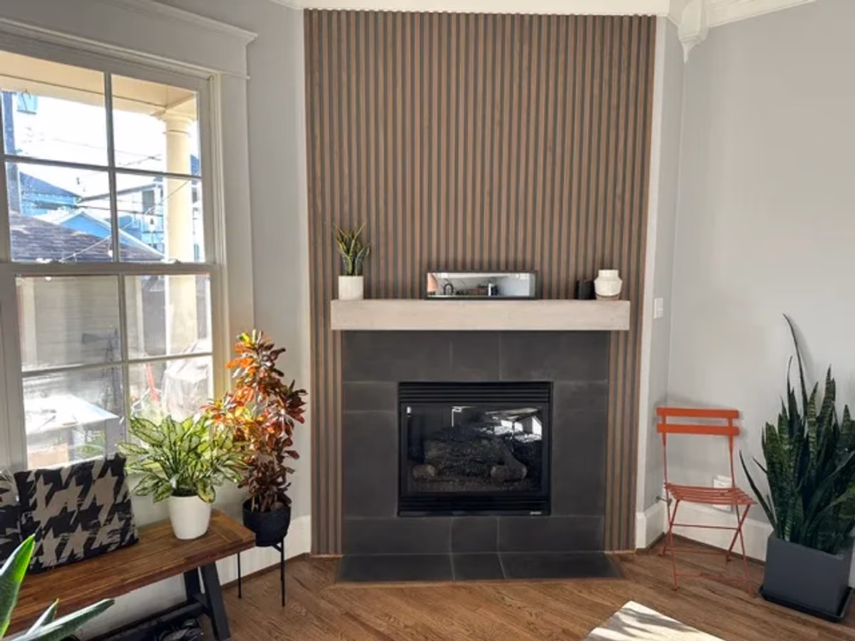 Renovated living area with a vertical wood-slat feature wall, a tiled fireplace with a wood mantel, and houseplants